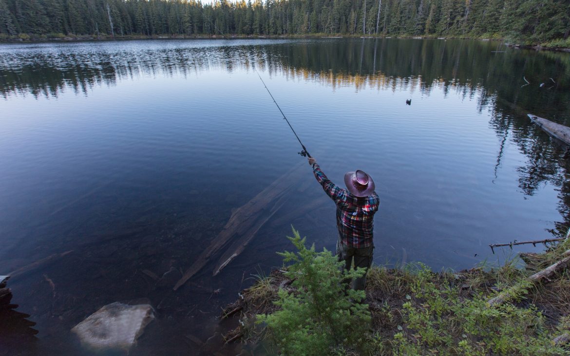 a man casts a line in a scenic lake