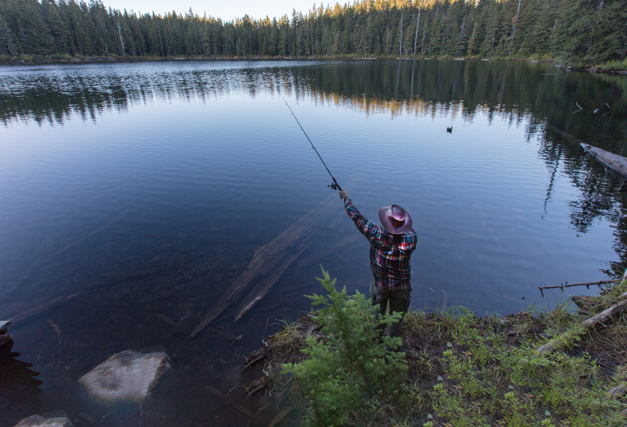 a man casts a line in a scenic lake