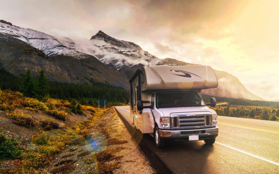 RV Leaks and Shaky Fivers -- RV on a highway winding through snow-capped mountains