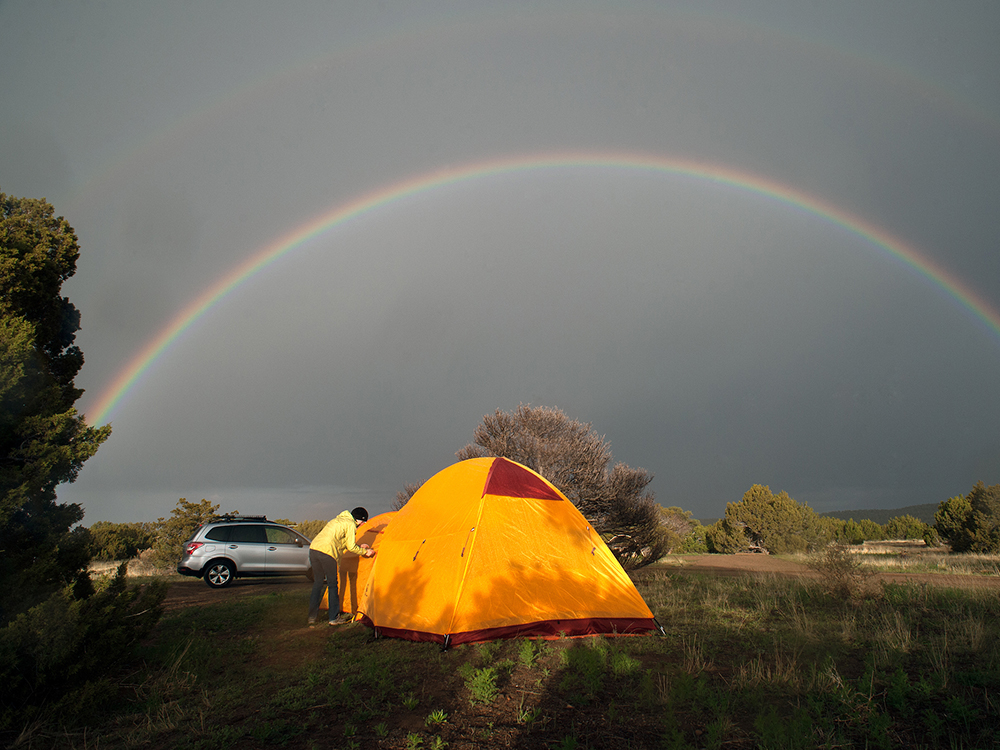 A yellow dome tent with a rainbow gracefully arcing in the background.