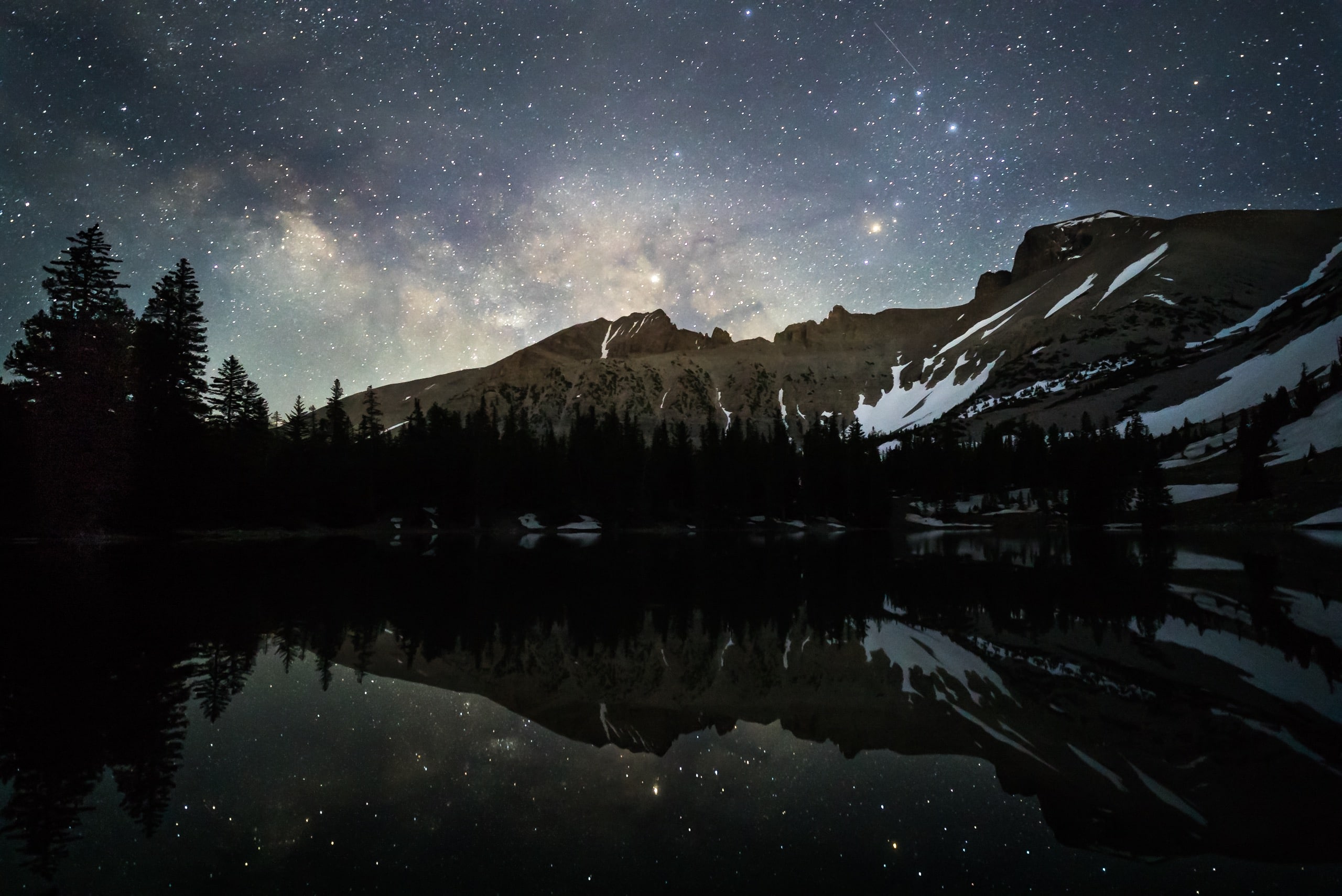 A mountain ridge frams a sky dense with stars.