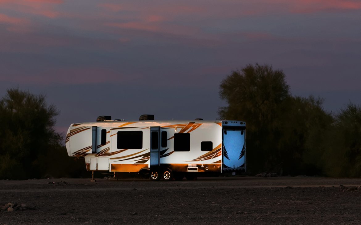 selecting a vehicle to tow — A toy hauler trailer on a field at dusk.