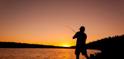 Man casts a line as the sun rises on the horizon.