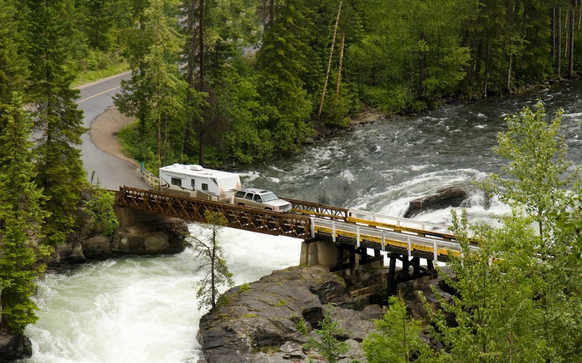 RV towing a fifth-wheel drives over a bridge