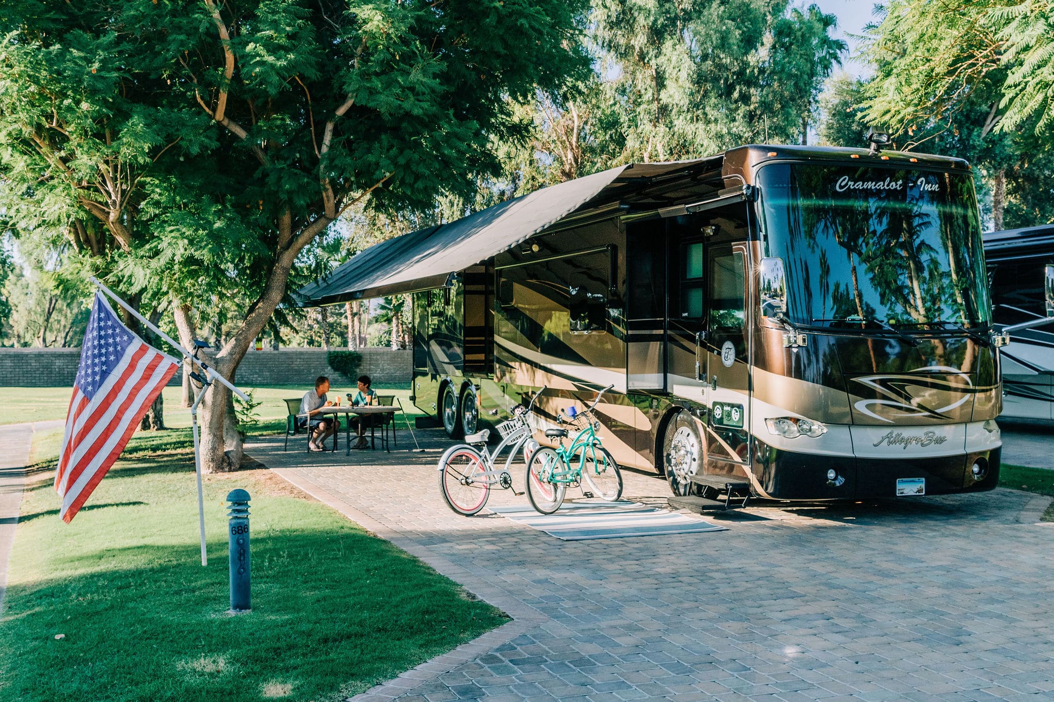 A motorhome with awning on a brick-paved site.