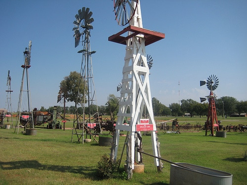 A series of windmills on a green prairie.