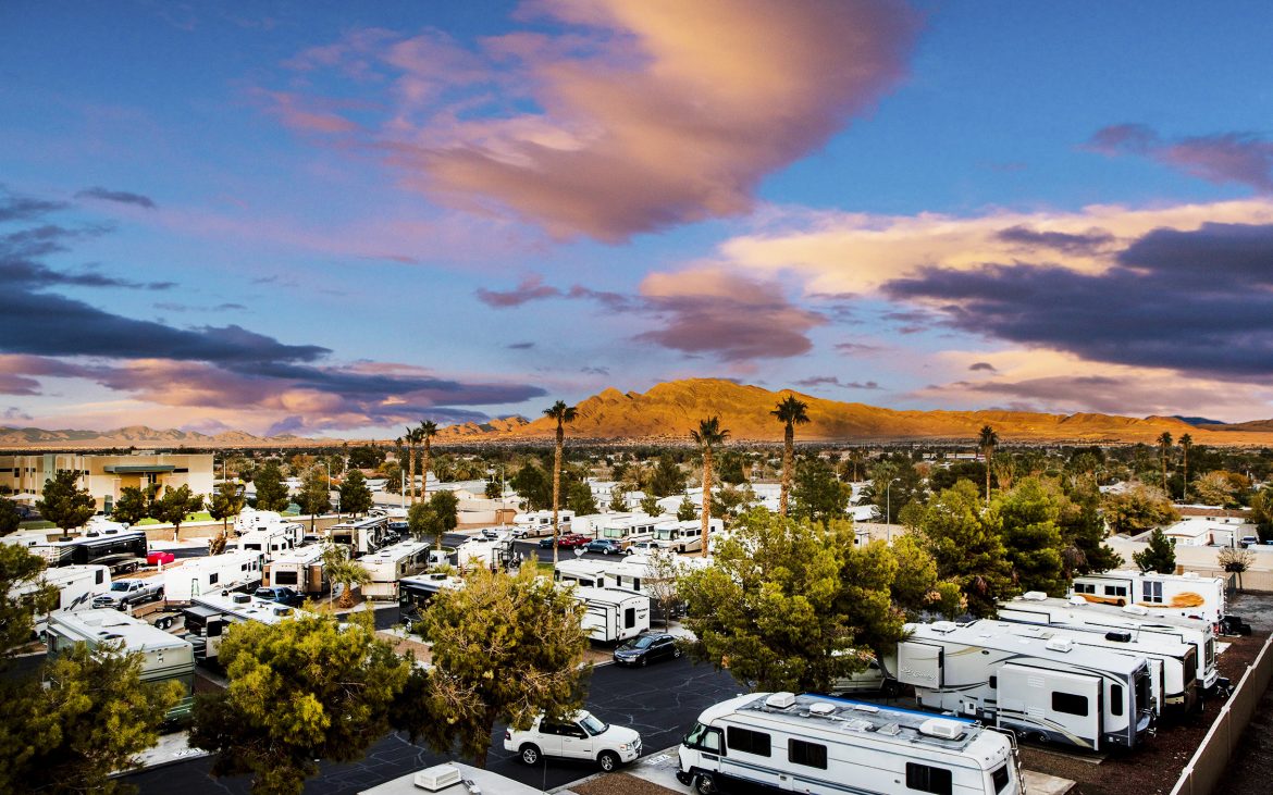 RV park sprawls under a blue sky with rugged mountains in background.