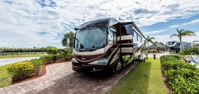 Florida fun to your weekends —Motorhome parked on a brick pad flanked by lush grass.