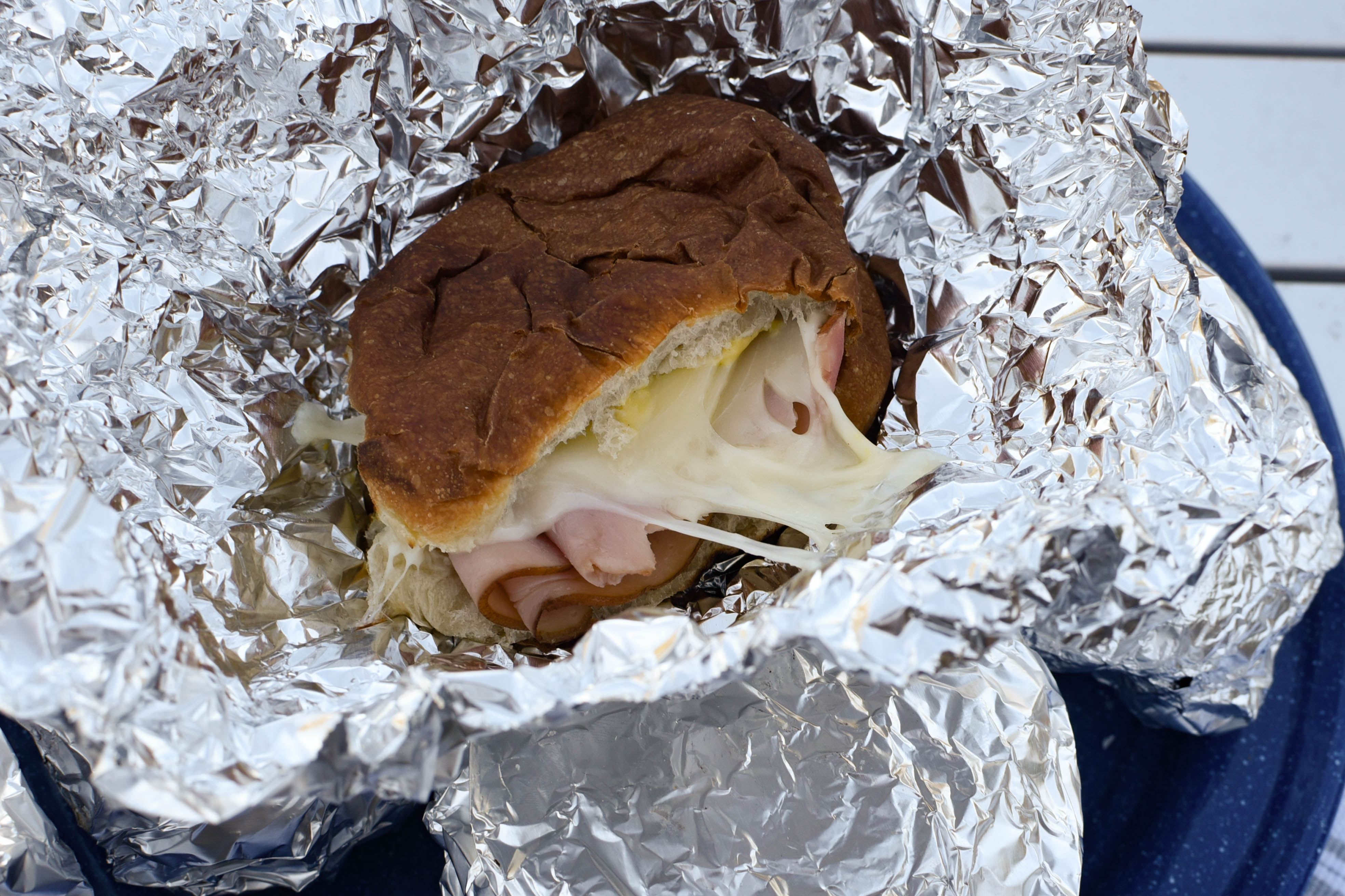 Sandwich with gooey cheese in foil.