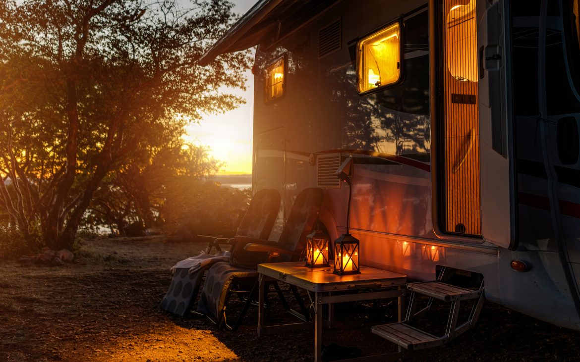 Practice good manners — An RV casts a welcoming glow onto a dusk campsite.