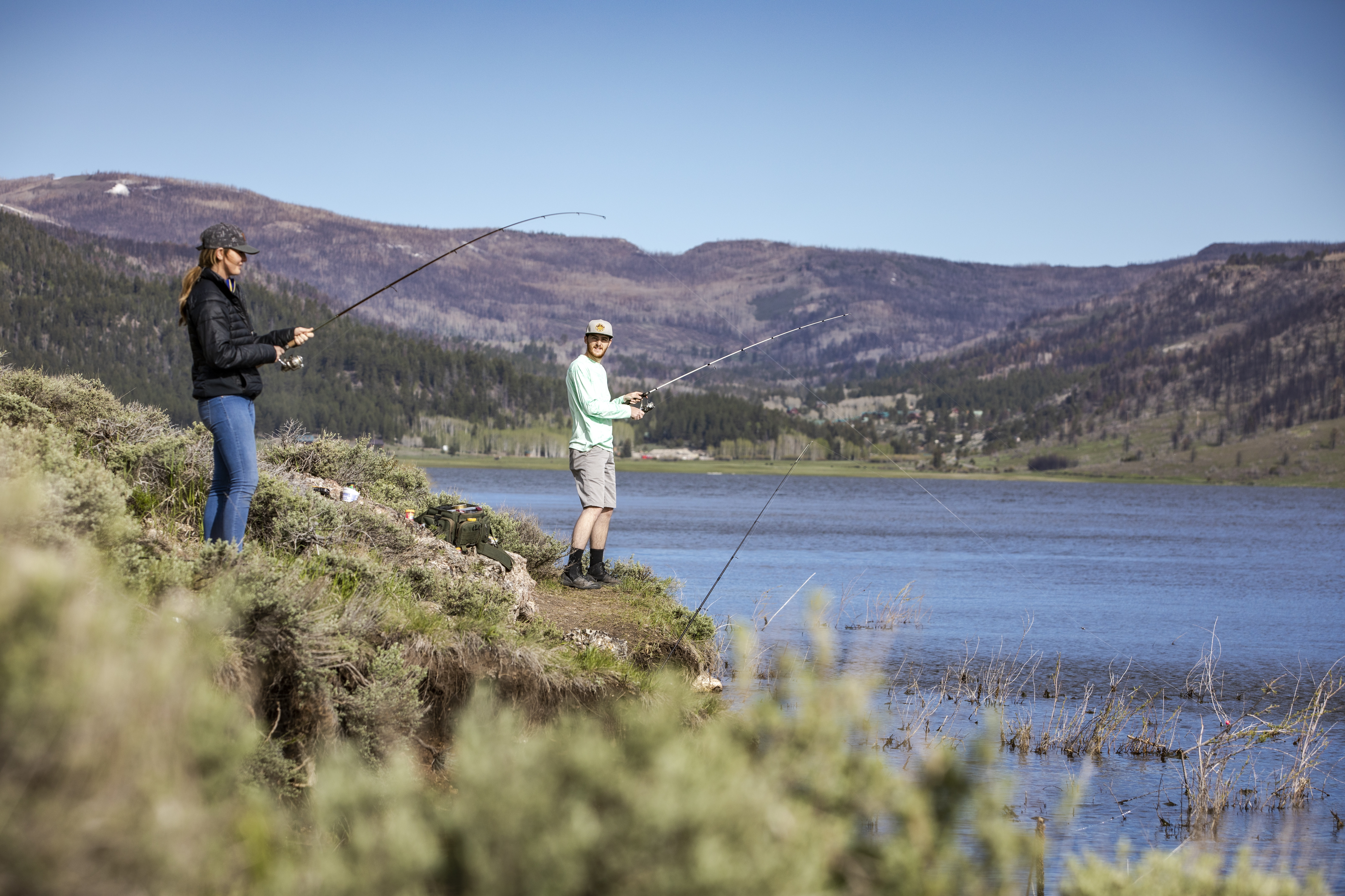 A man and woman fishing on a calm lake.