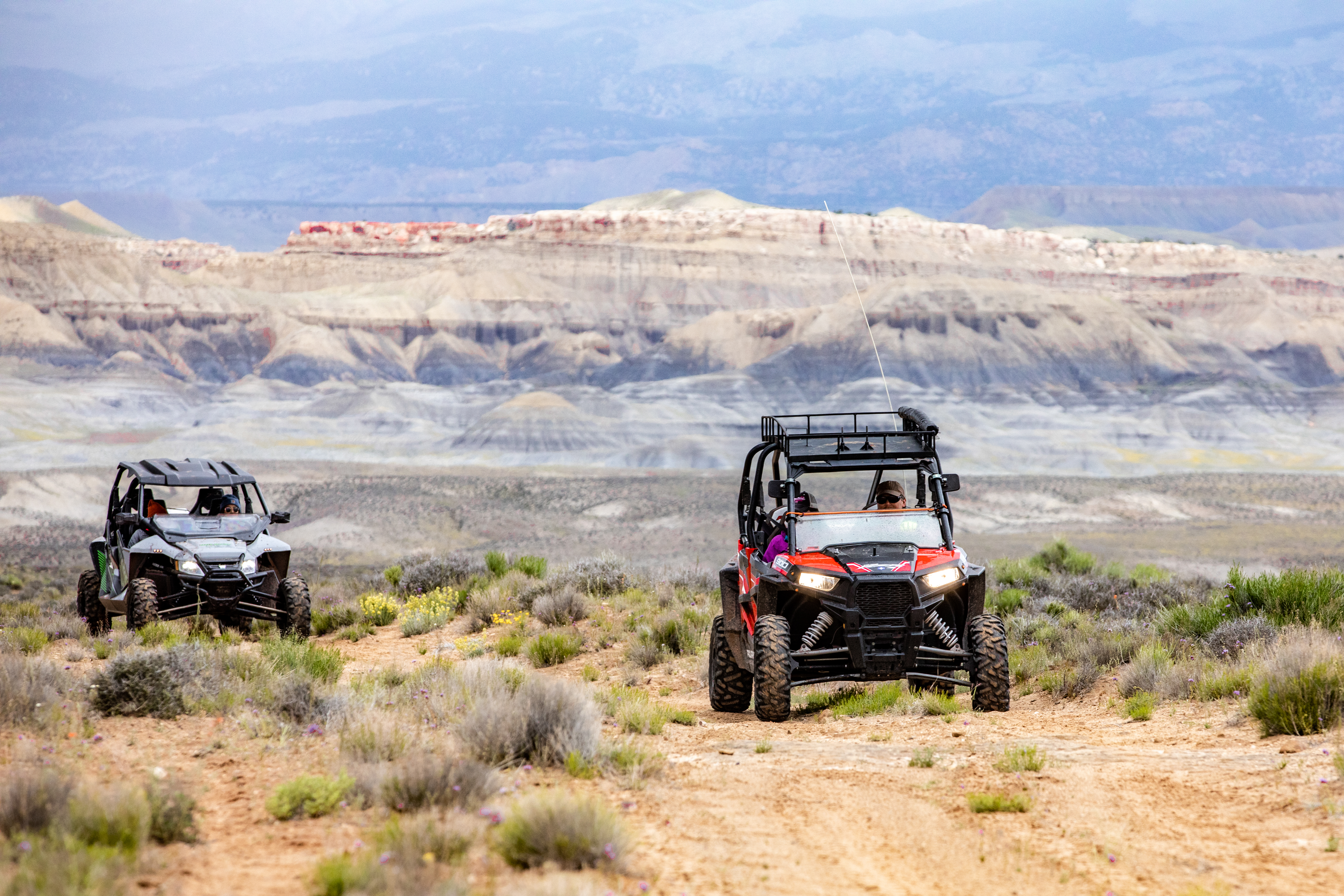 A pair of ATVs speeding across rugged countryside.