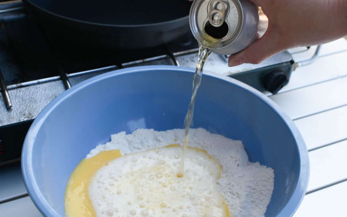 Can of beer pouring into bowl of flour and egg