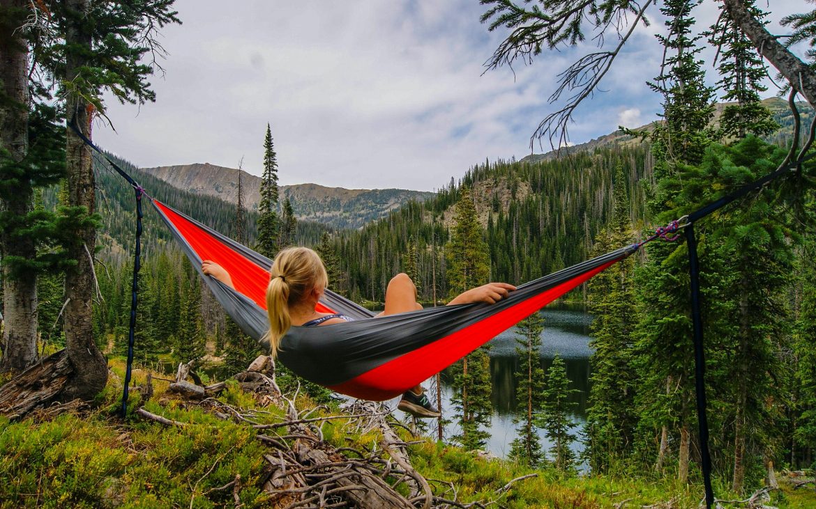 Woman relaxing in hammock near lake