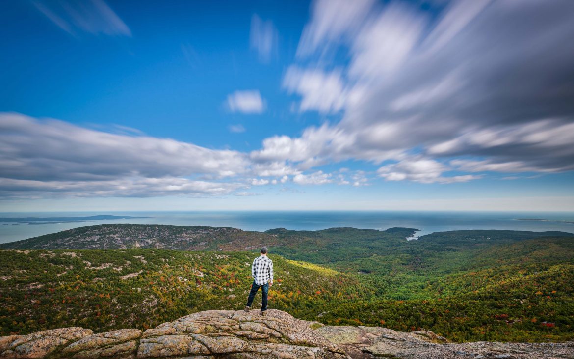 Coast of Maine — Man overlooks mountain vista as clouds race by.