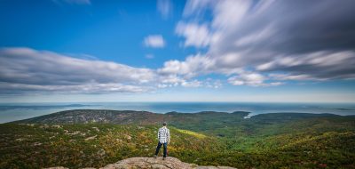 Coast of Maine — Man overlooks mountain vista as clouds race by.