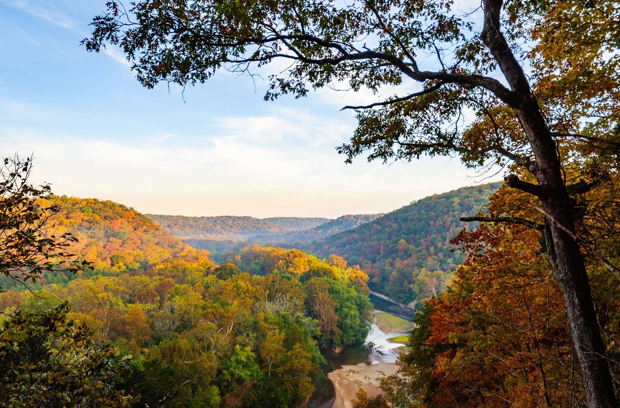 A river runs through a valley during fall colors.