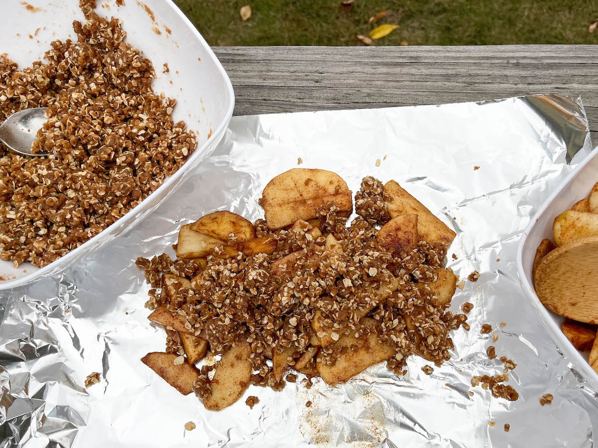 Apples on a sheet of aluminum foil under a pile of crumbles.