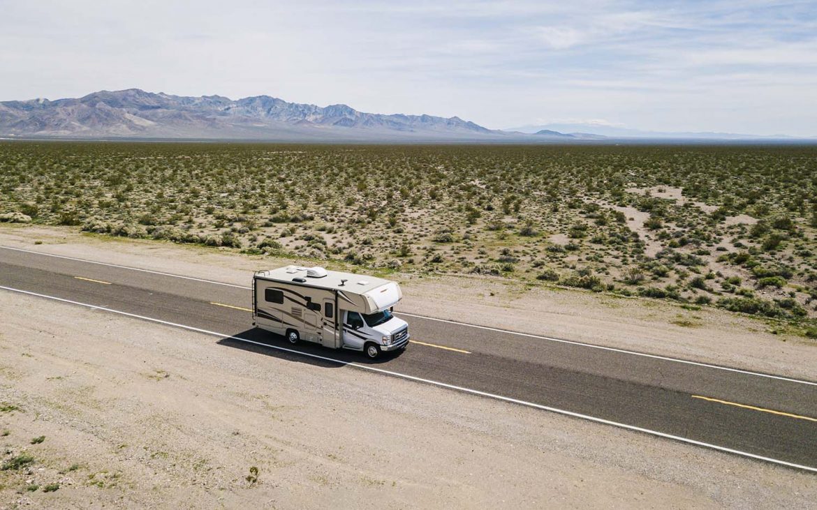 Class C motorhome driving down a desert highway.