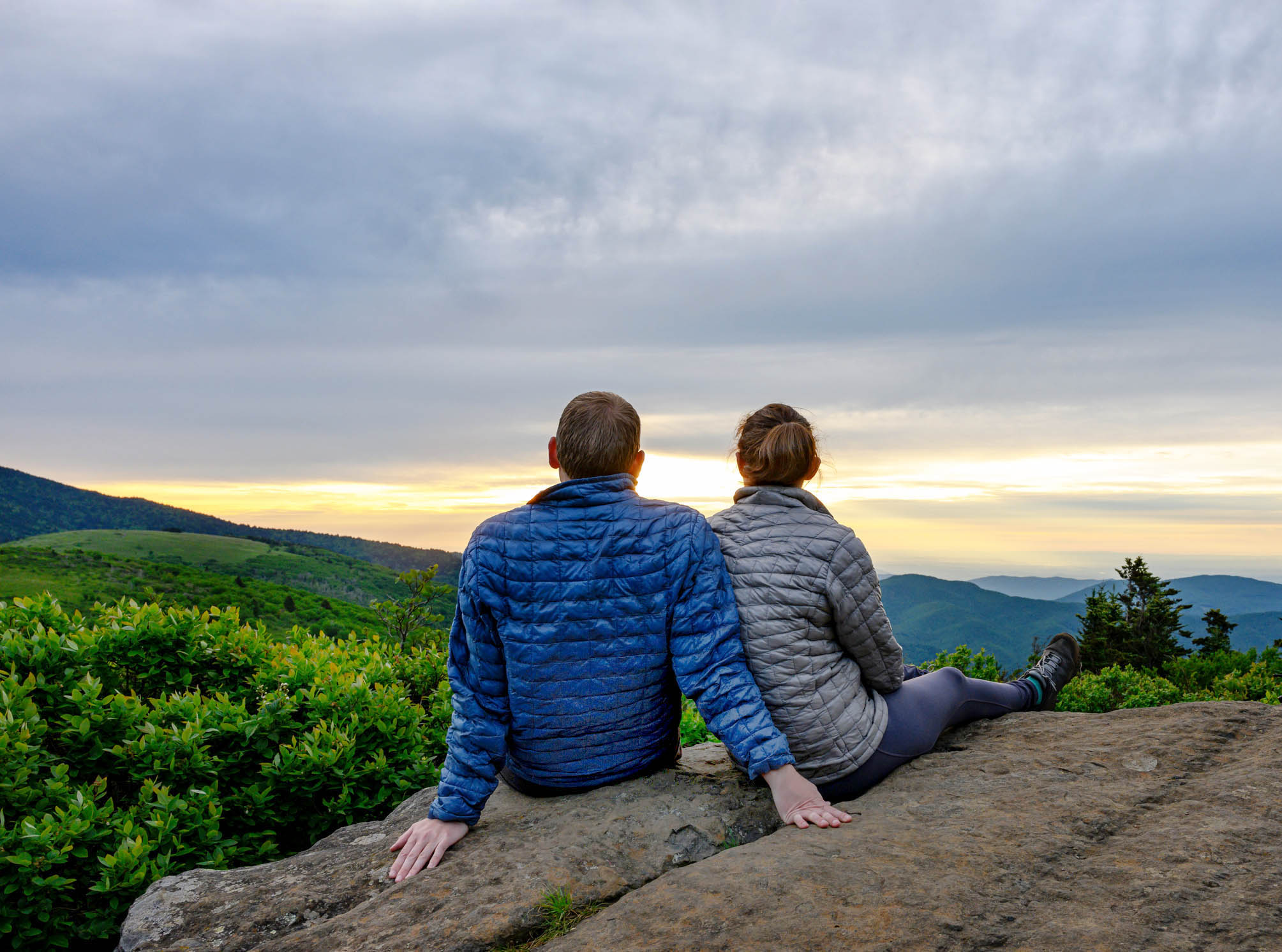 A couple on a rock admiring a vast vista