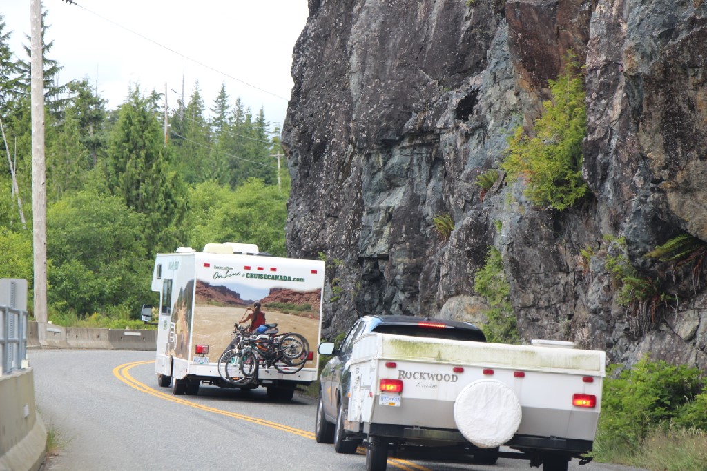 A vehicle pulling a folding camping trailer driving close to a Class C motorhome.