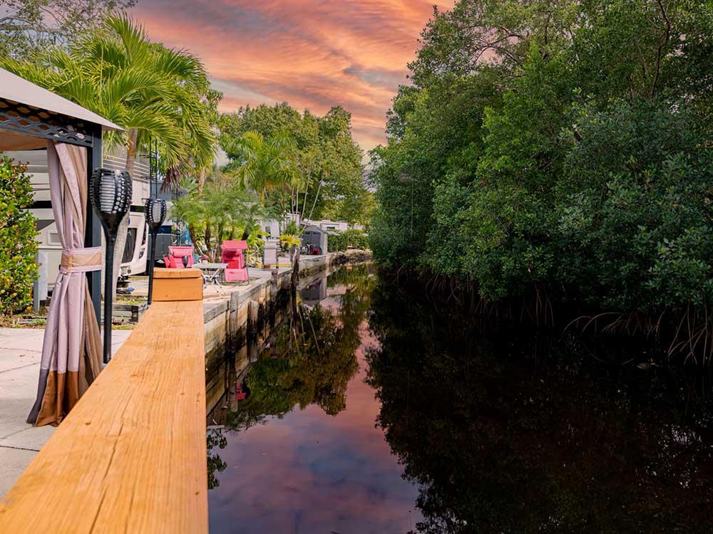 A canal under red dusk skies borders RV spaces.