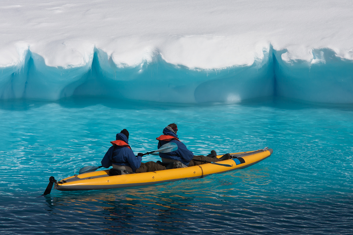 Two men kayaking near a glacier
