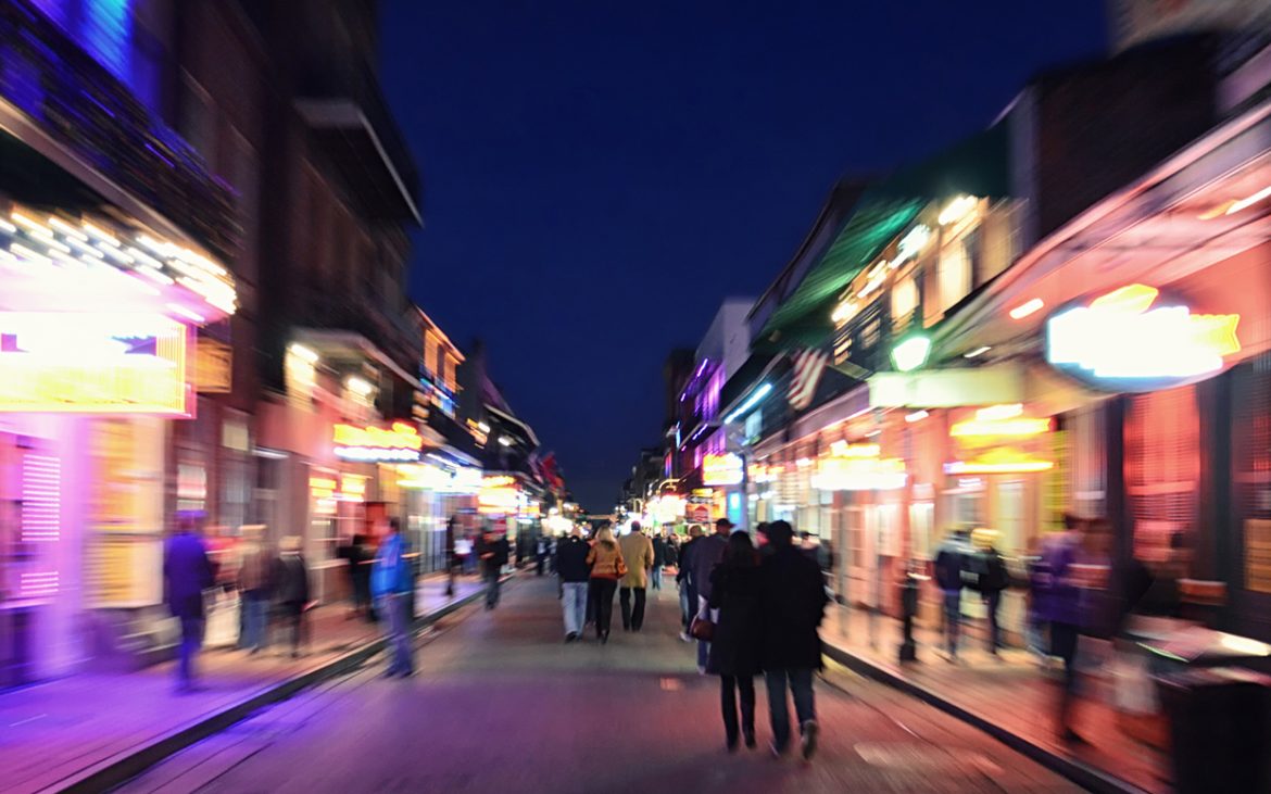 Crowds stroll a neon-lit street