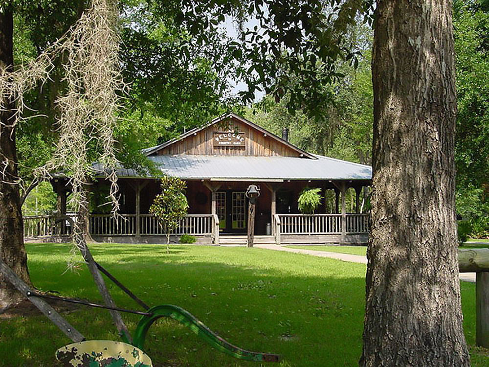 Country Oaks RV Park and Campground —A homey wooden building on a lush green lawn.