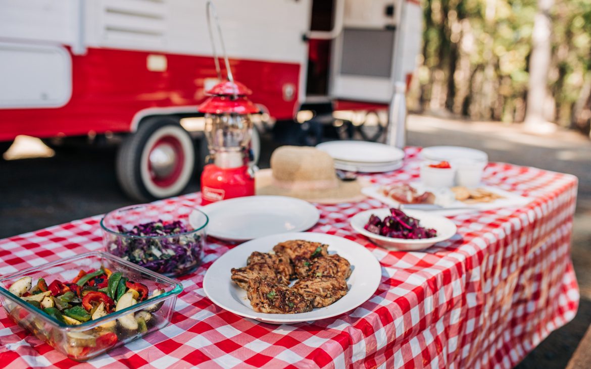 Feast on a Red and White Tablecloth by an RV in the Forest