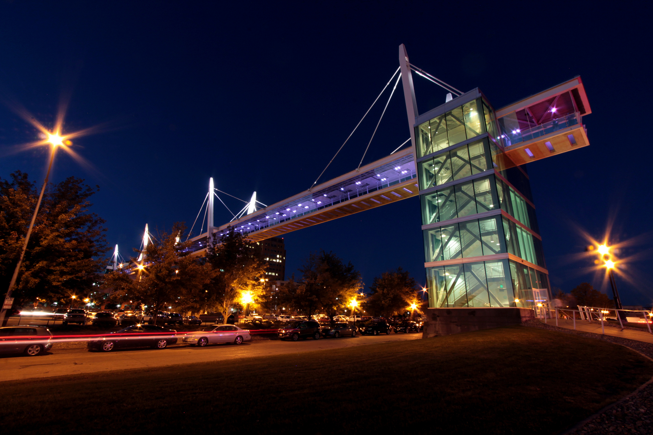 A night shot of an illuminated footbridge over a side river. 