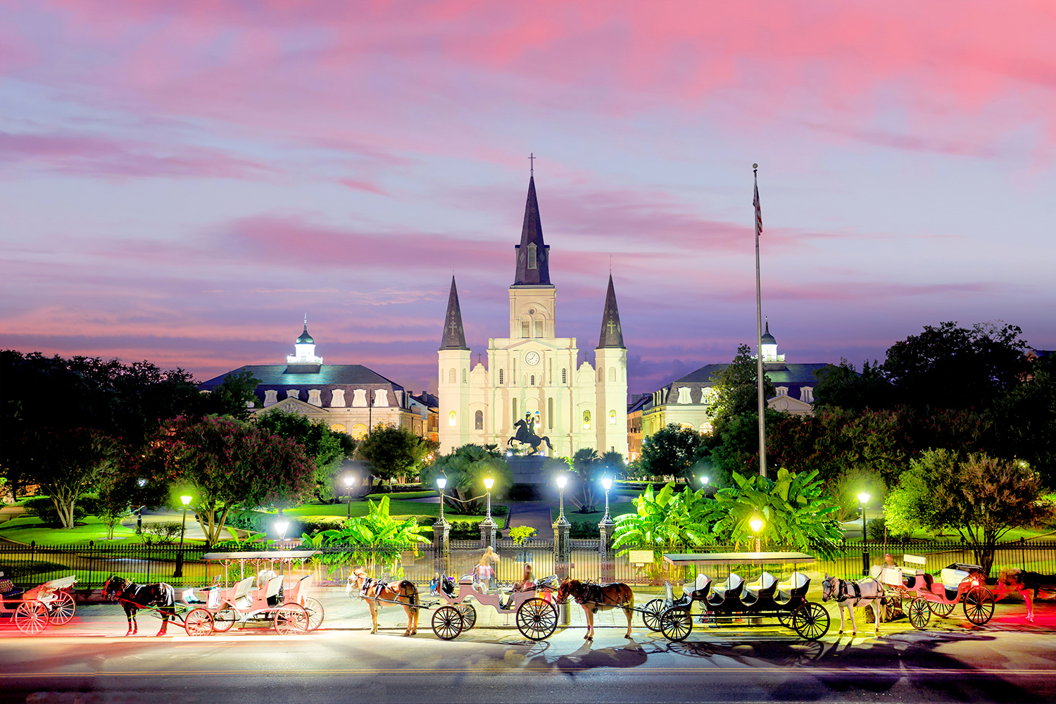 Sunset over an elegant cathedral with horse carriages in foreground.