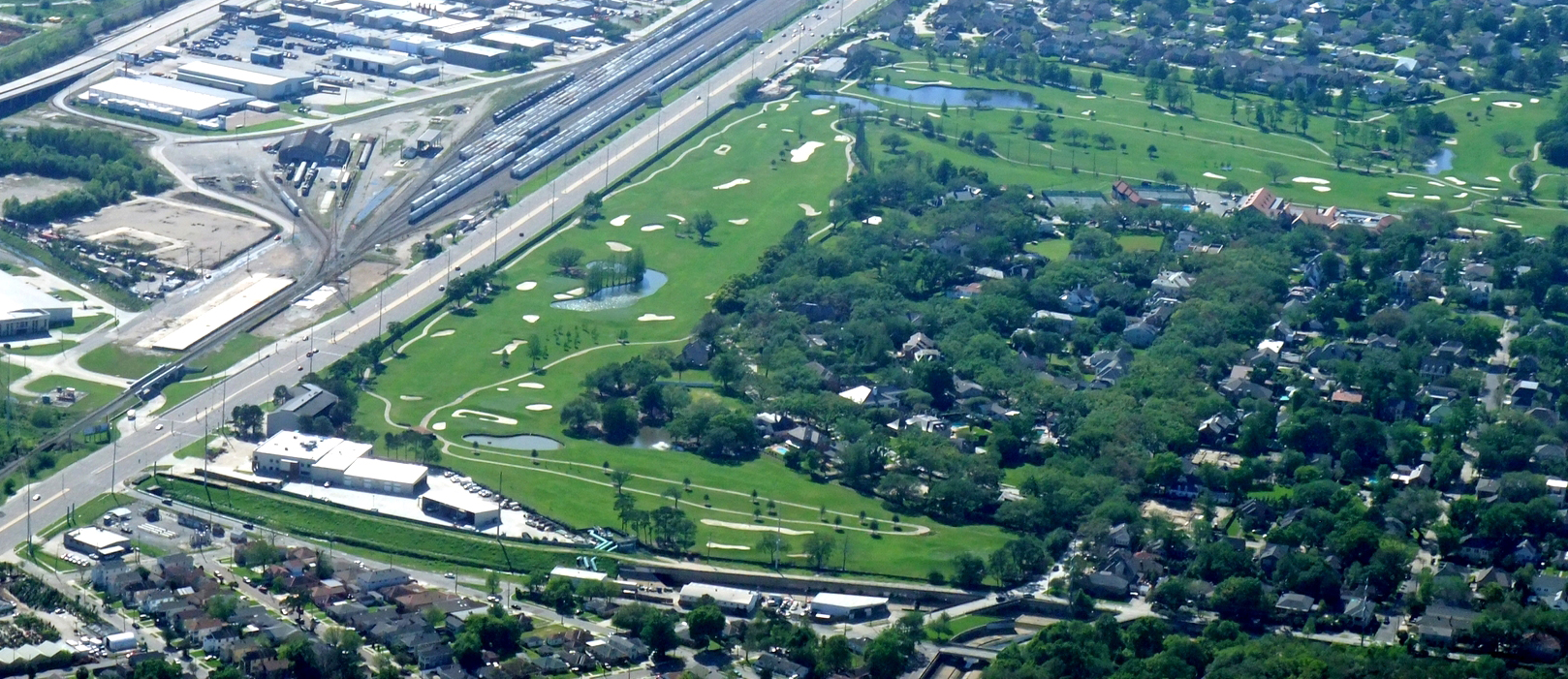 Aerial view of a golf course surrounded by buldings.