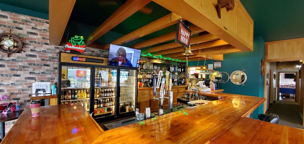 A smooth wood bar stands in front of a variety of beer taps.