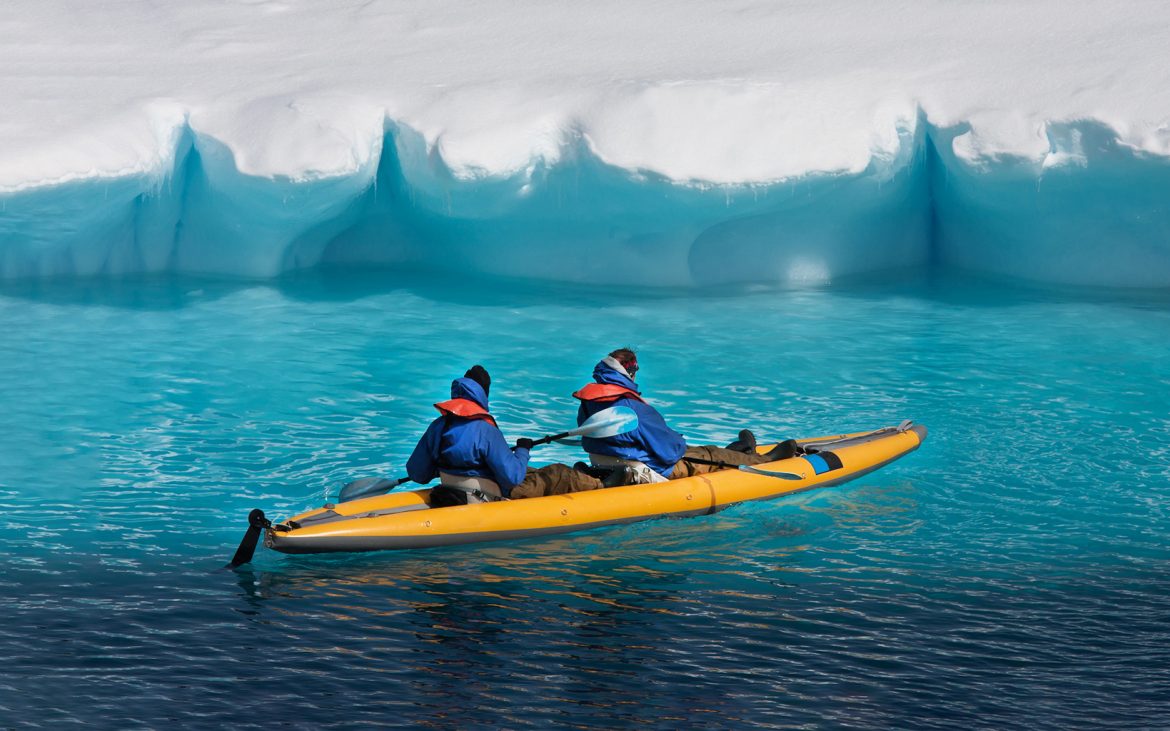 Two men in a kayak near a glacier