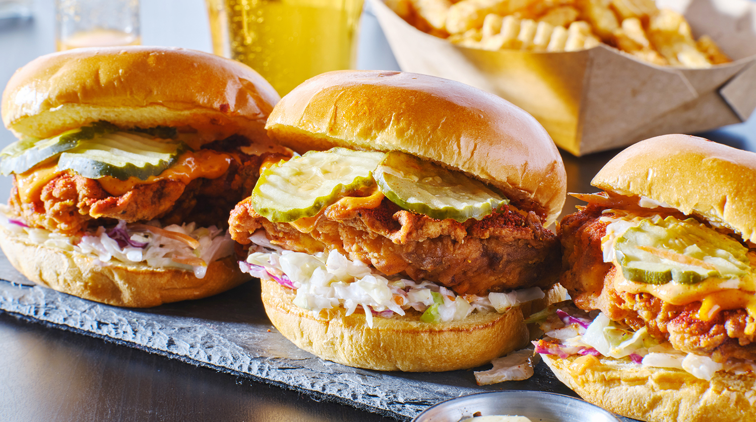 spicy nashville hot chicken sandwich with coleslaw and pickles in a row