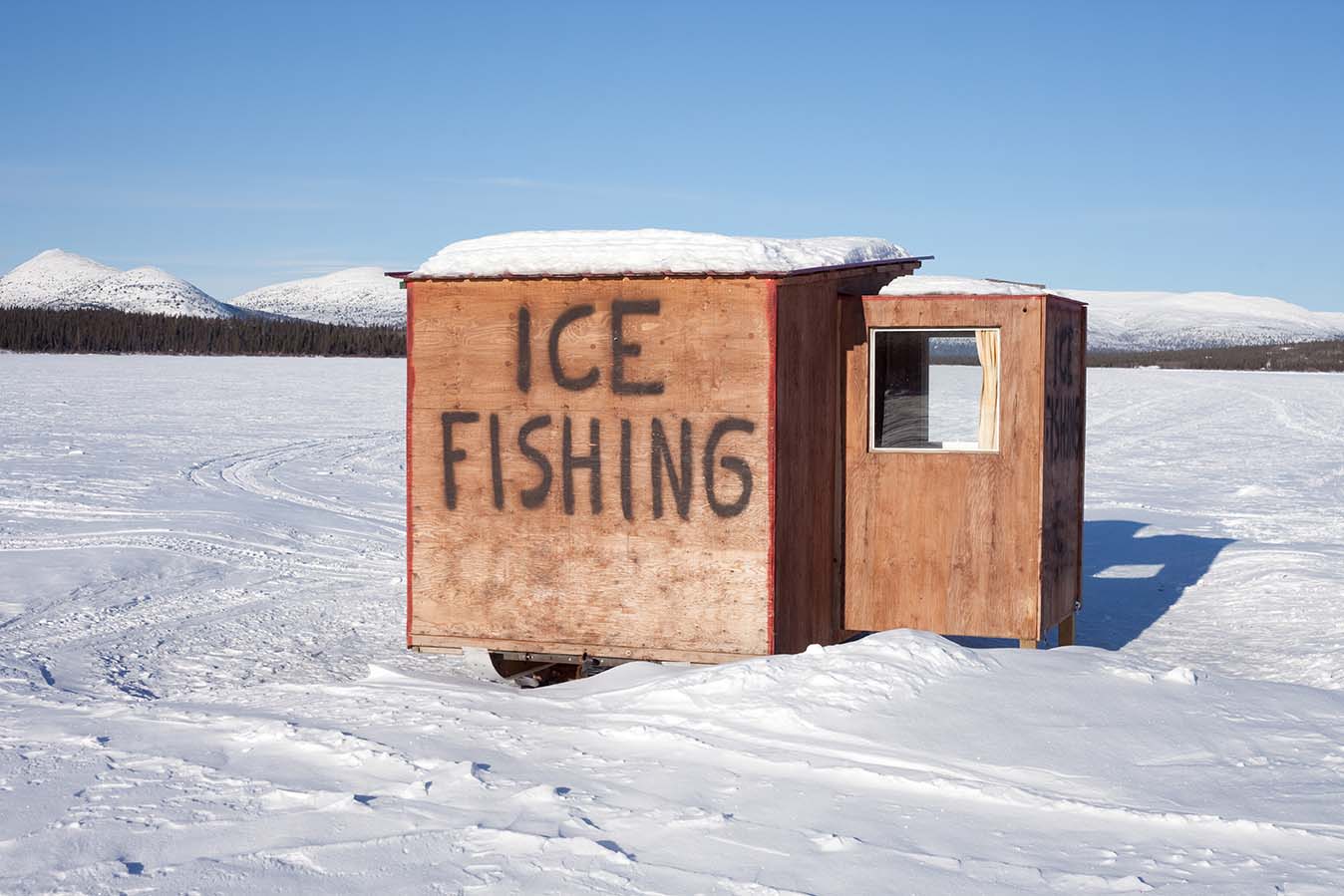 A wheeled shack on the ice with "Ice Fishing" written on the side.
