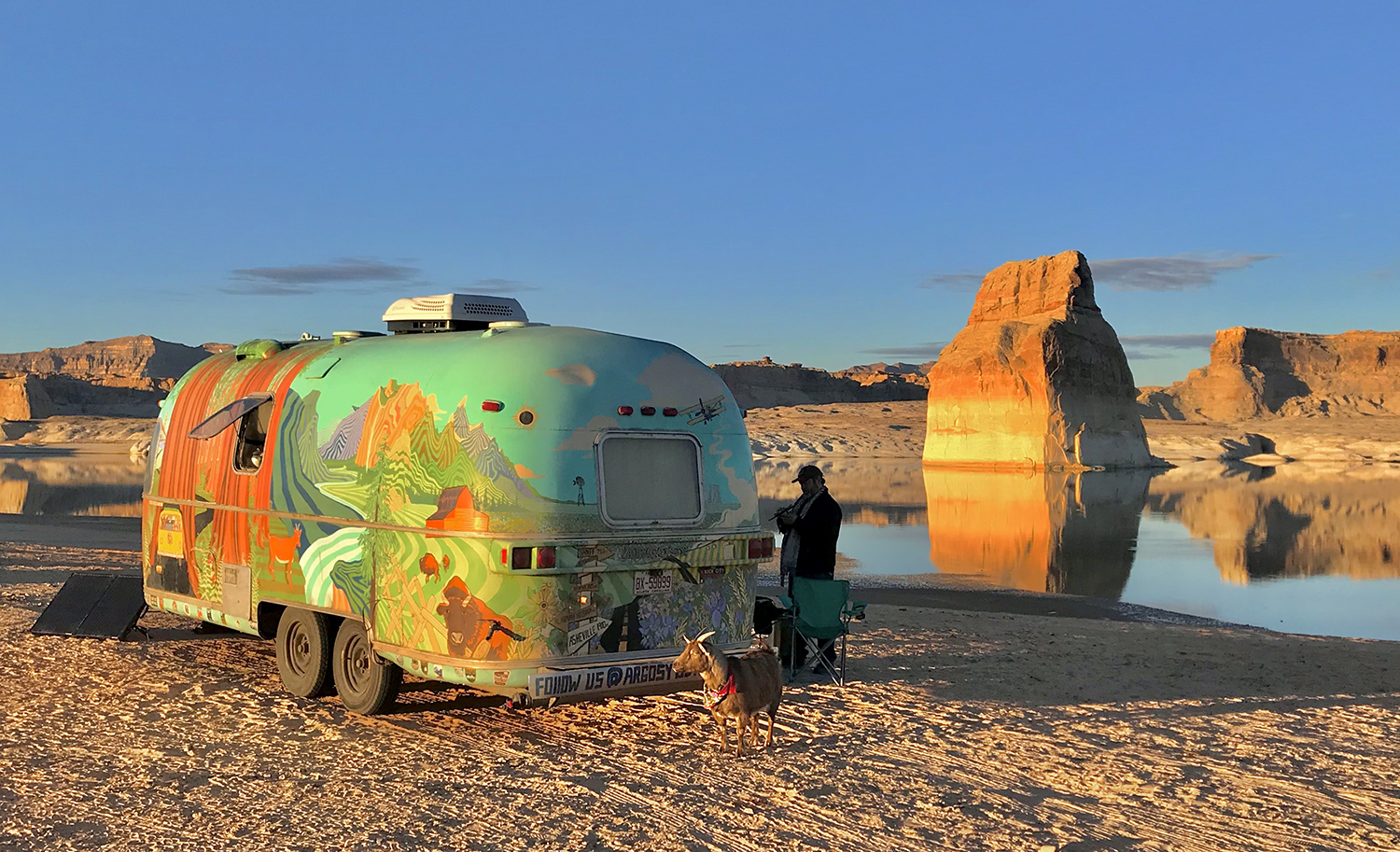 A colorful RV parked on a desert lakeshore.