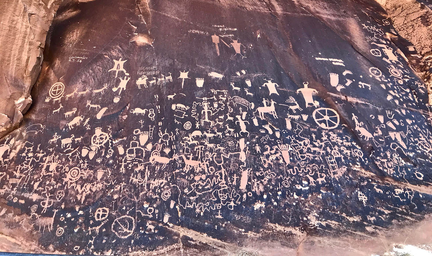 A cluster of petroglyphs adorn the surface of a rock face.