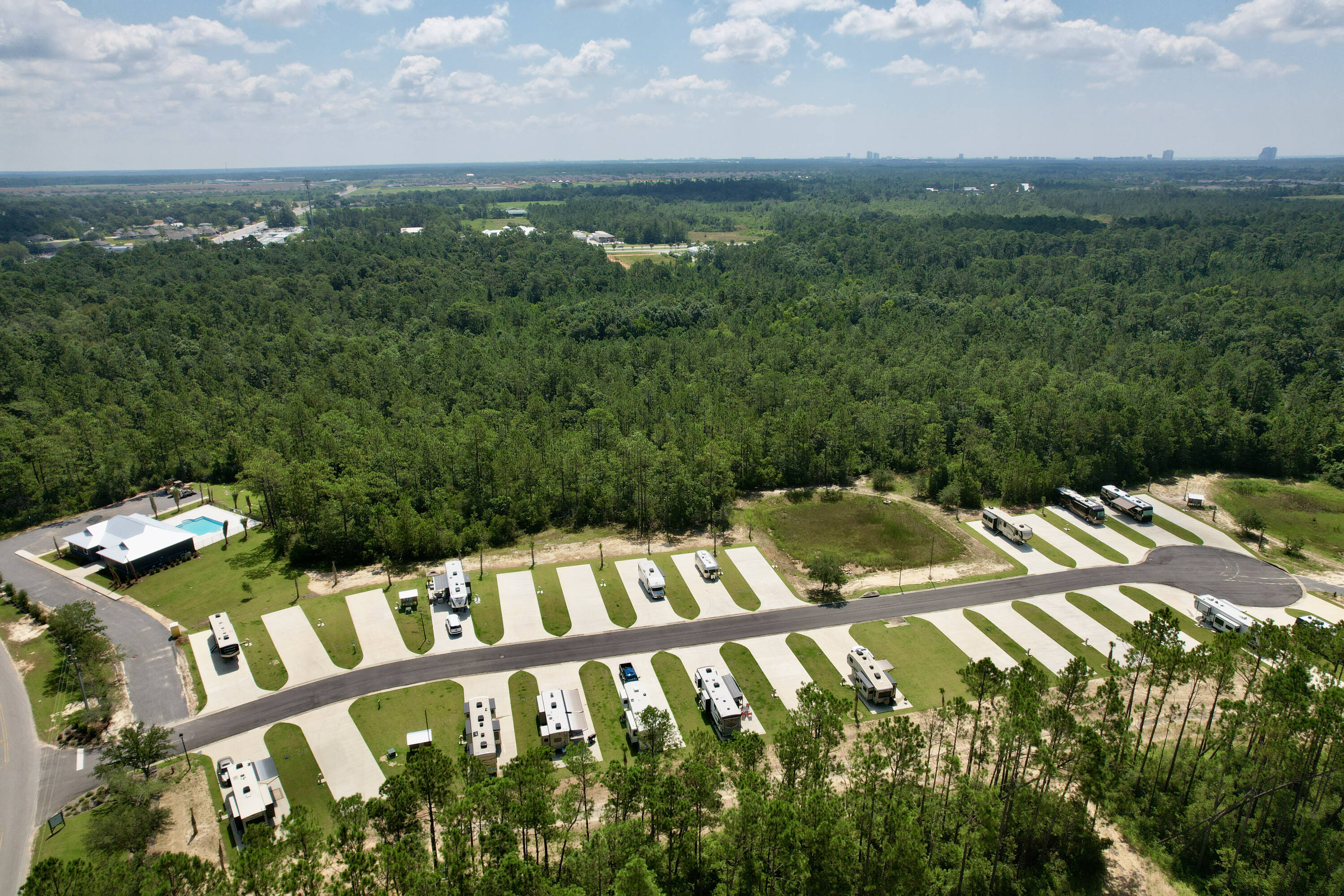 Aerial shot of an RV park with pool surrounded by tall trees.