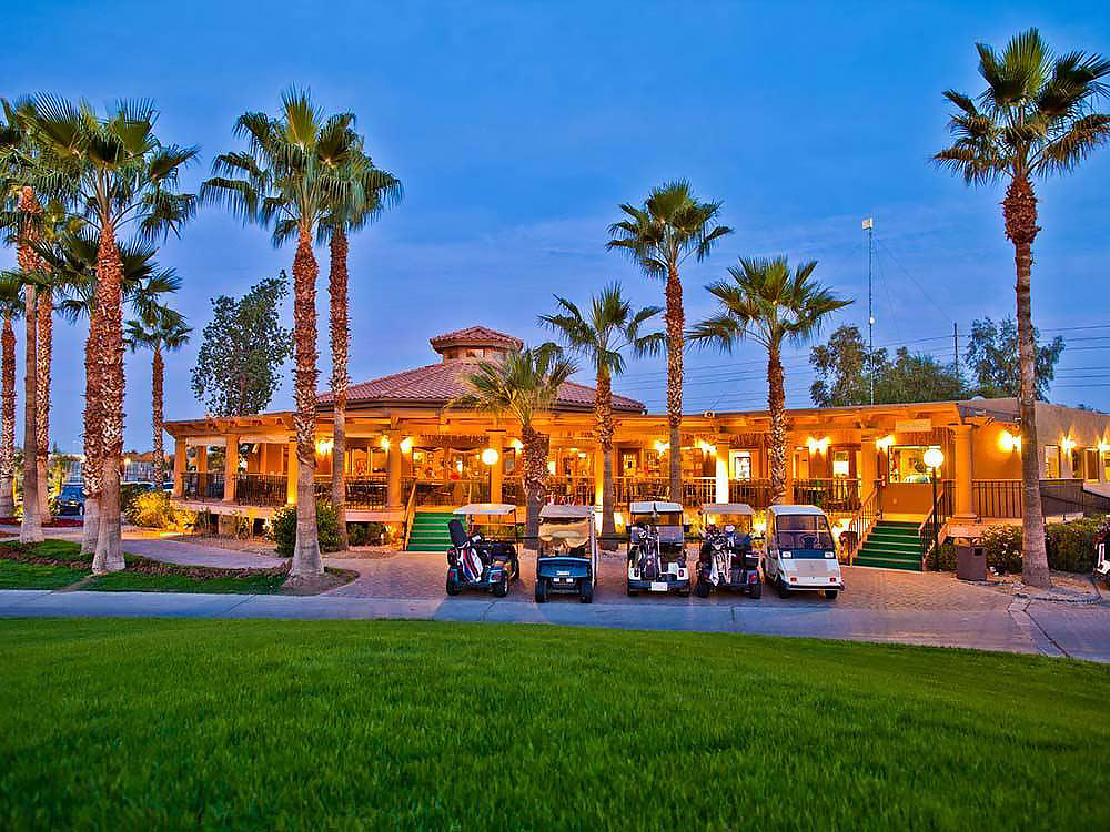 A golf clubhouse with golf carts at sunset. 
