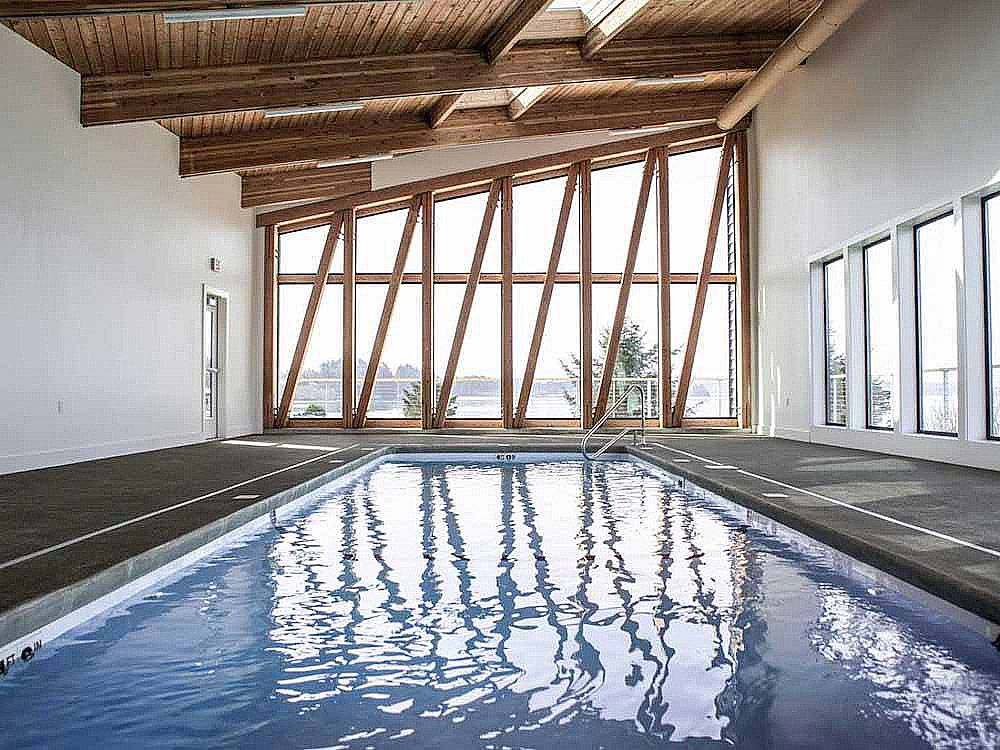 Rectangular indoor swimming pool with floor-to-ceiling window.