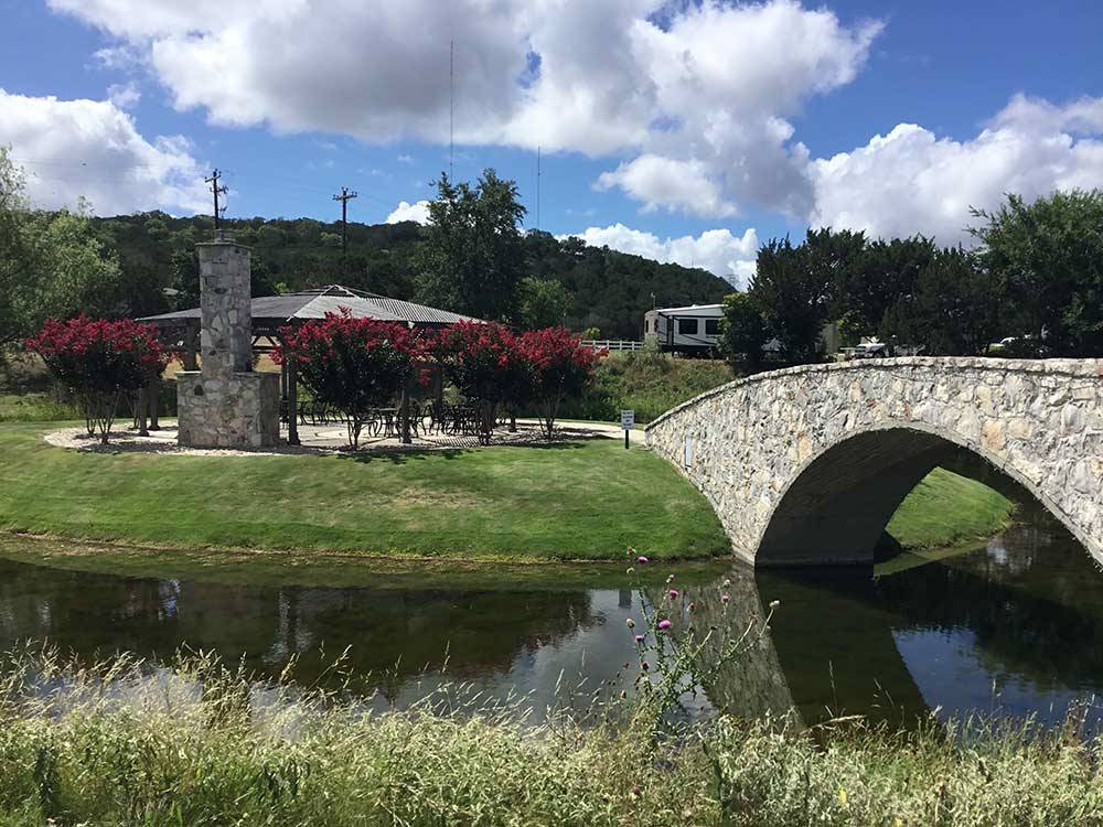 A stone bridge crosses a calm creek and leads to an RV park.