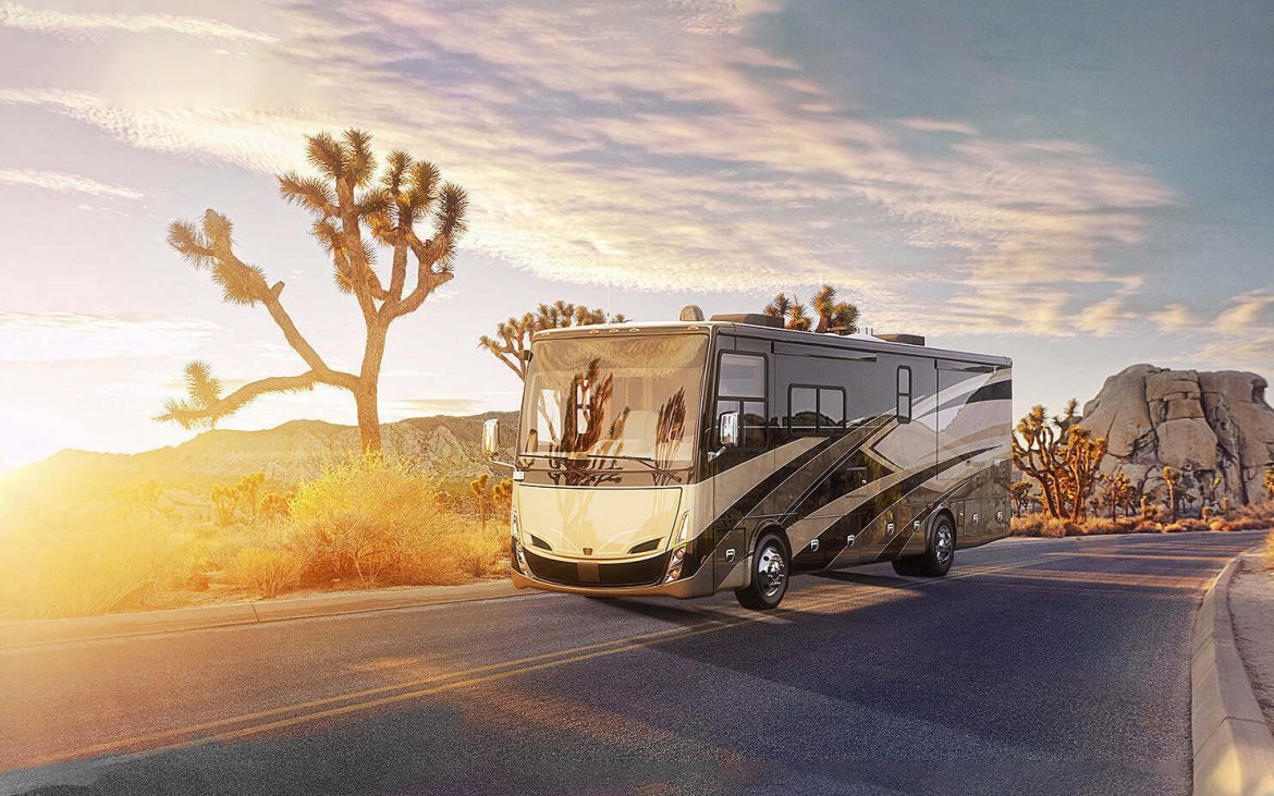 motorhome driving down a desert road with Joshua Trees in the background