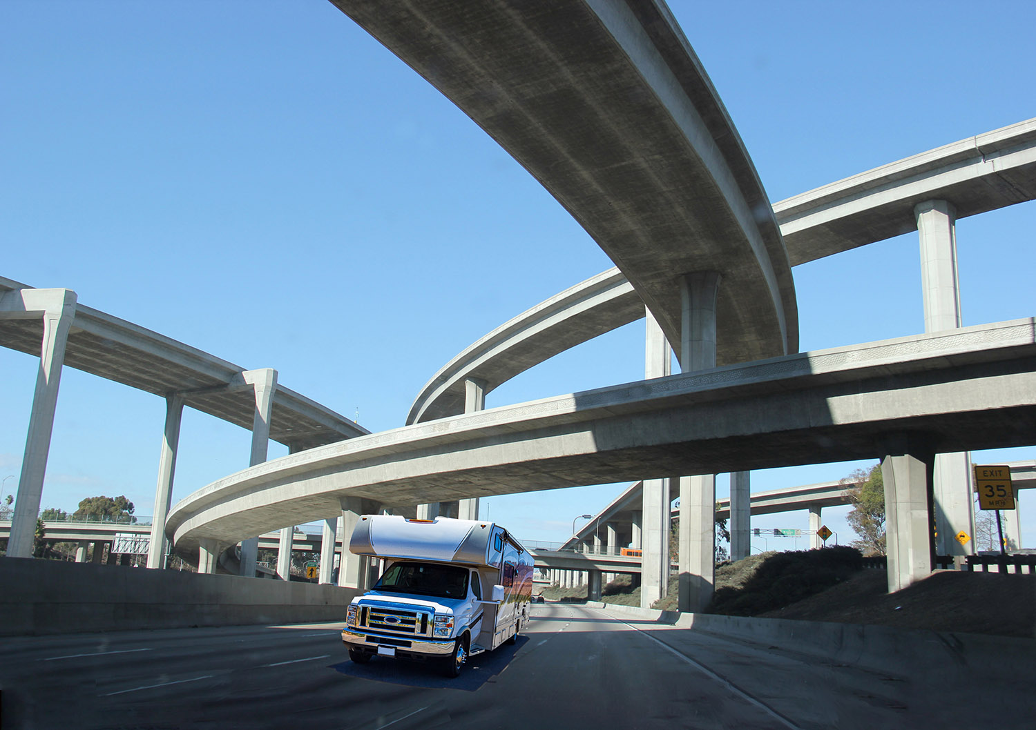 RV driving under several overpasses on a clear interstate.