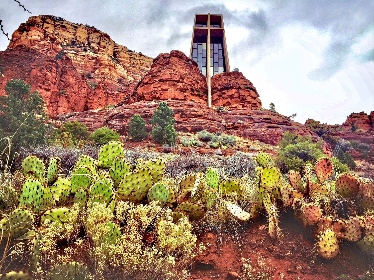 A cathedral-like structure rising among the red rocks of a mountain face.