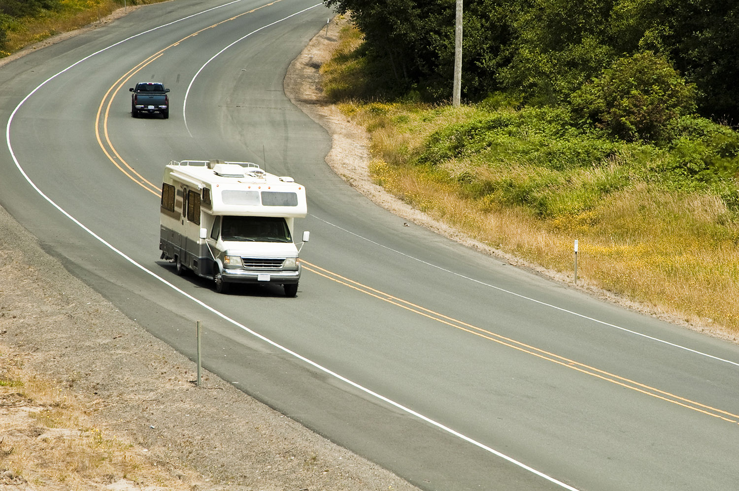An RV taking a curve on a rustic highway.