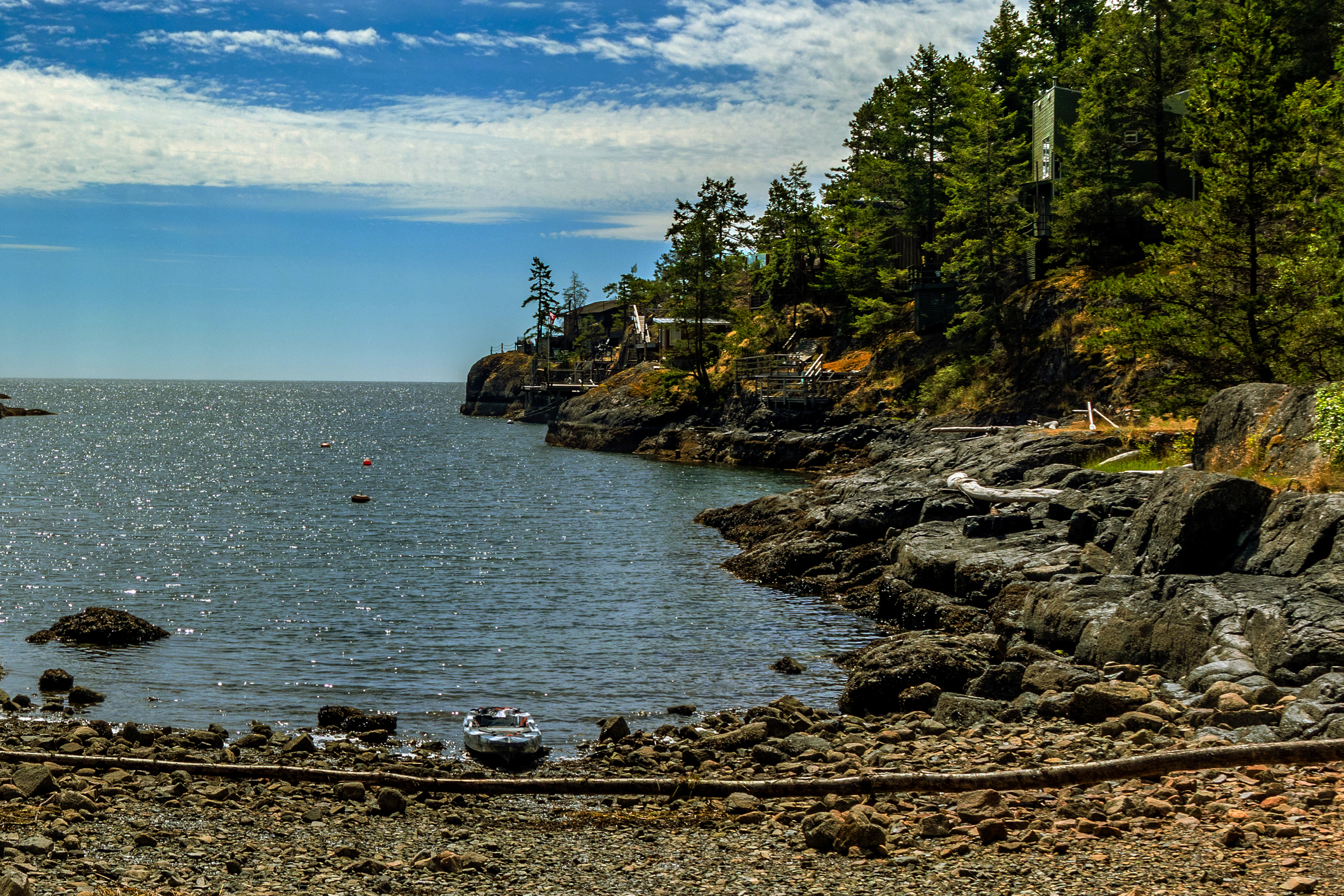 A boat beached on a rocky coastline that gives way to thick forest.