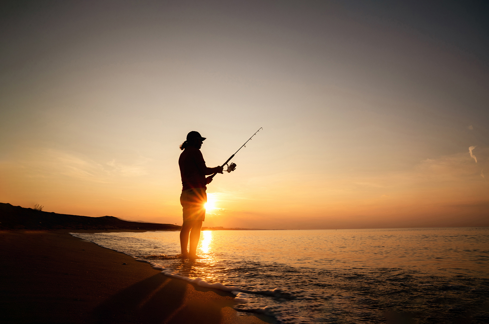 Fishing during sunrise on the beach.