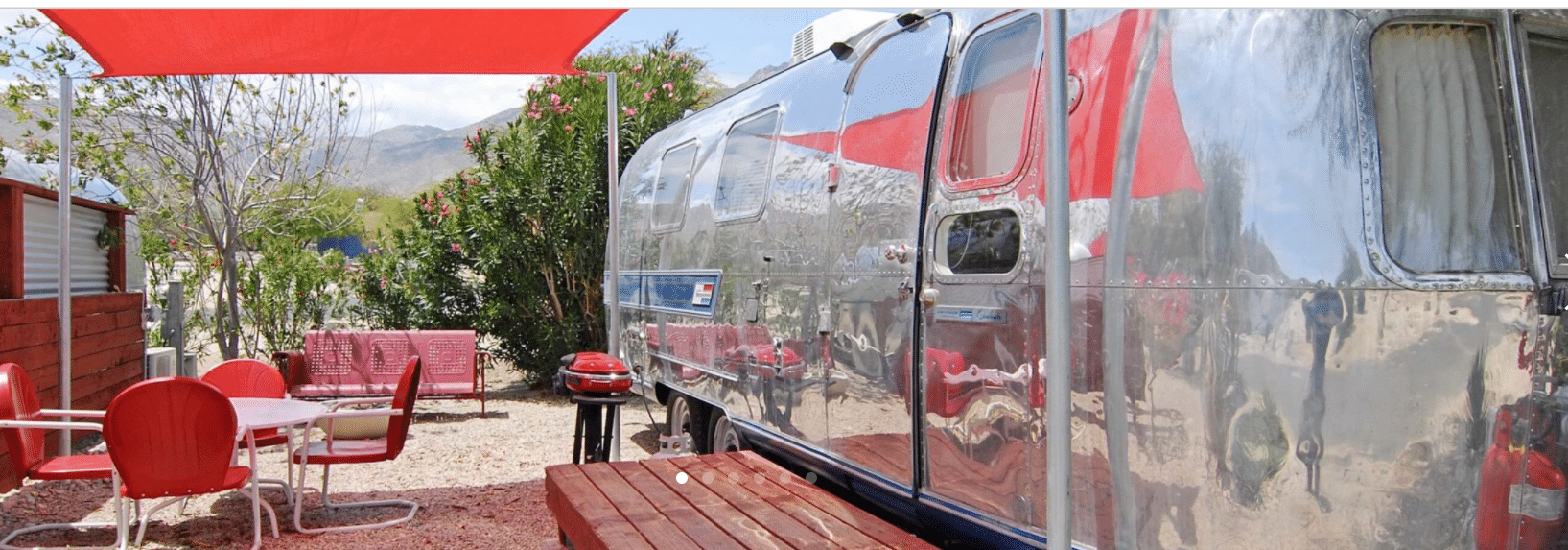 A vintage airstream parked in a site surrounded by vintage furniture.